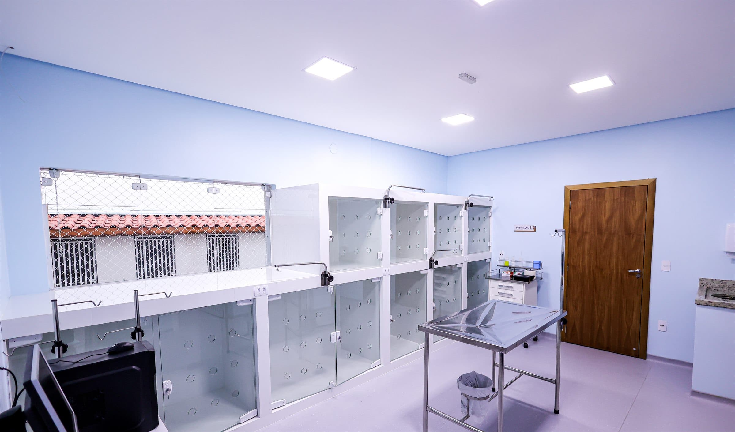 Sala de internação do Centro Veterinário, com baias de vidro individuais e mesa de aço inoxidável
